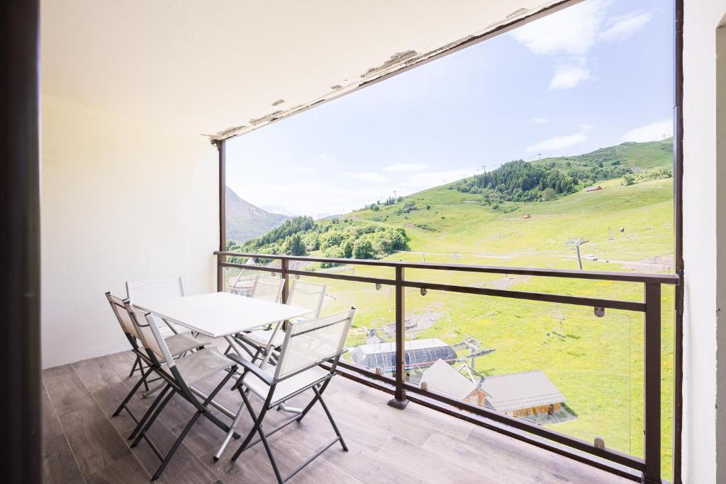 un balcon avec une table et des chaises et une grande fenêtre dans l'établissement Le Chrystal des Neiges - Le Corbier - Vue pistes, à Villarembert