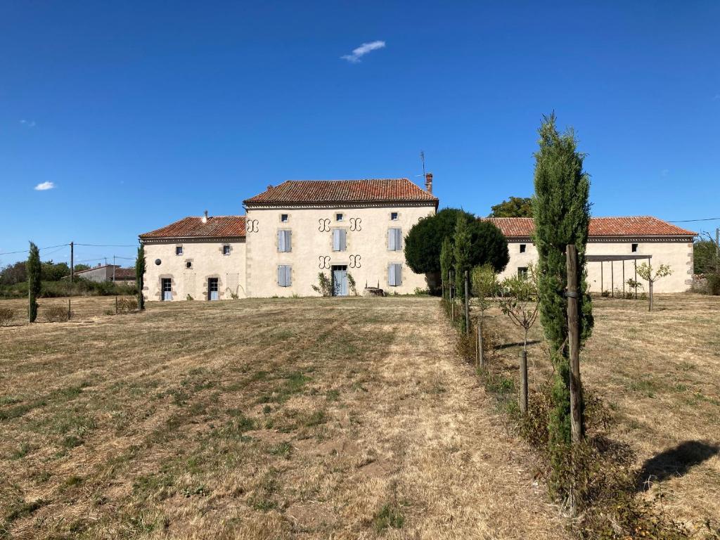 une grande maison blanche avec des arbres dans un champ dans l'établissement Gîte de Font Valet, à Millac