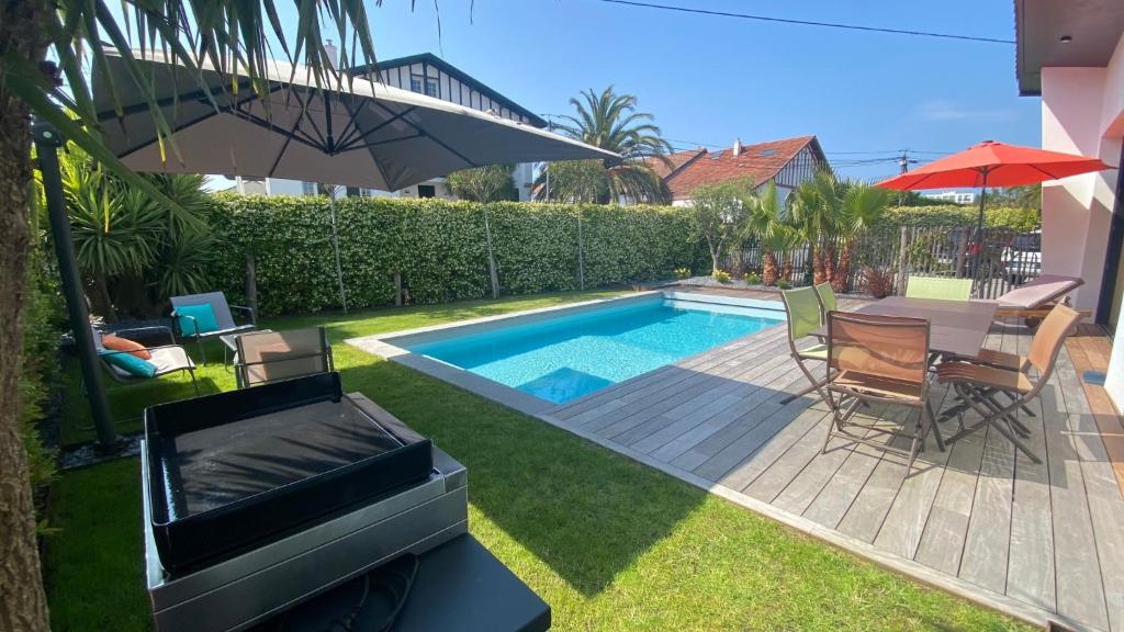 une cour avec une table et des chaises ainsi qu'une piscine dans l'établissement Villa Palma - Climatisée avec piscine, à Biarritz