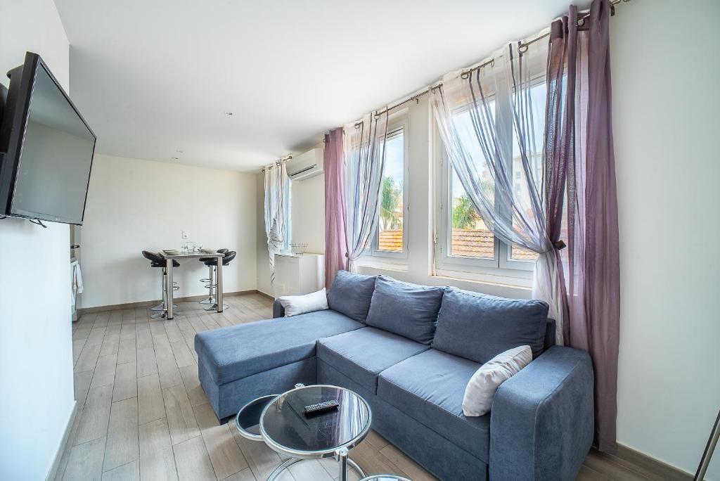 un salon avec un canapé bleu devant une fenêtre dans l'établissement Villa Welcom 4 - 2min à Pied de la Plage, à Canet