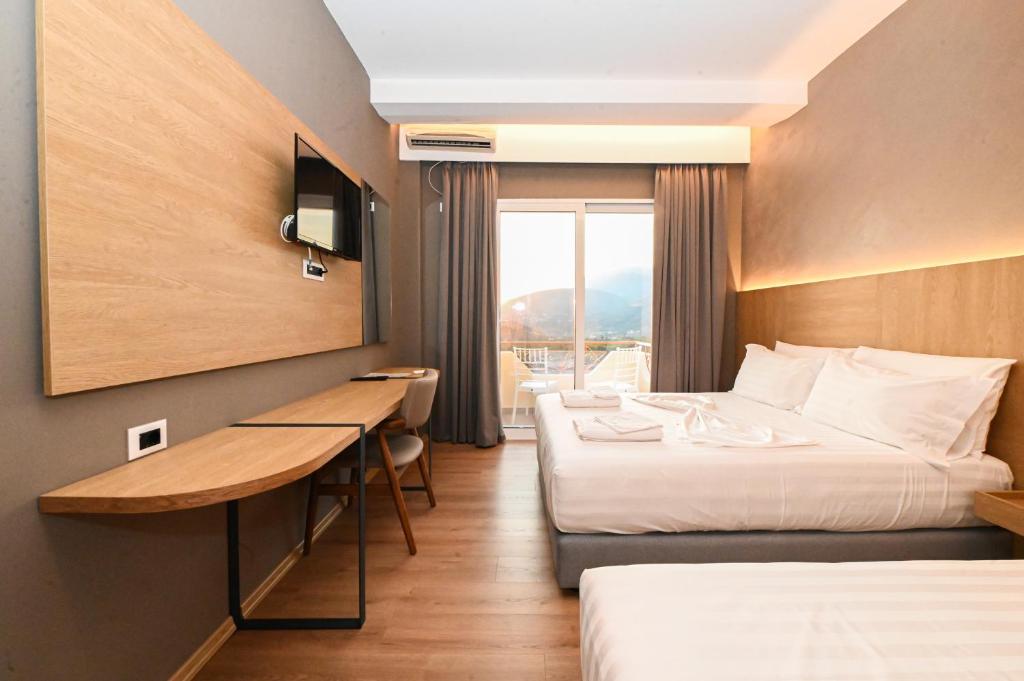 ein Hotelzimmer mit zwei Betten und einem Schreibtisch in der Unterkunft Hotel Panorama in Himarë