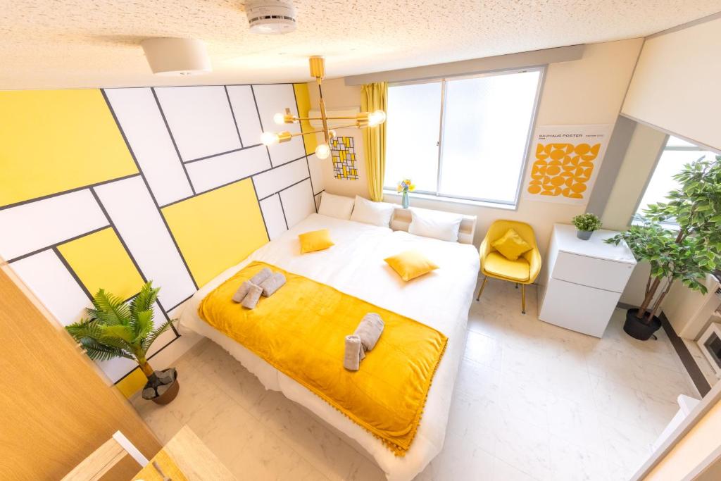 NarashinoにあるMakuhari & Tsudanuma Disney & Narita Airport Narashino by LEON RESORT 幕張 津田沼 習志野の黄色い毛布が掛けられた大きなベッドのある寝室