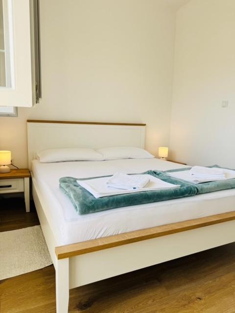 a white bed with two towels on top of it at Apartman Sanja in Vlašići