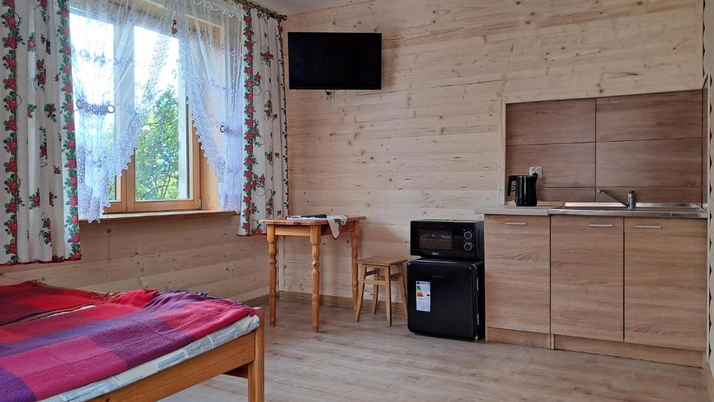 a bedroom with a kitchen and a table in a room at Dom Wczasowy U Góralki in Murzasichle