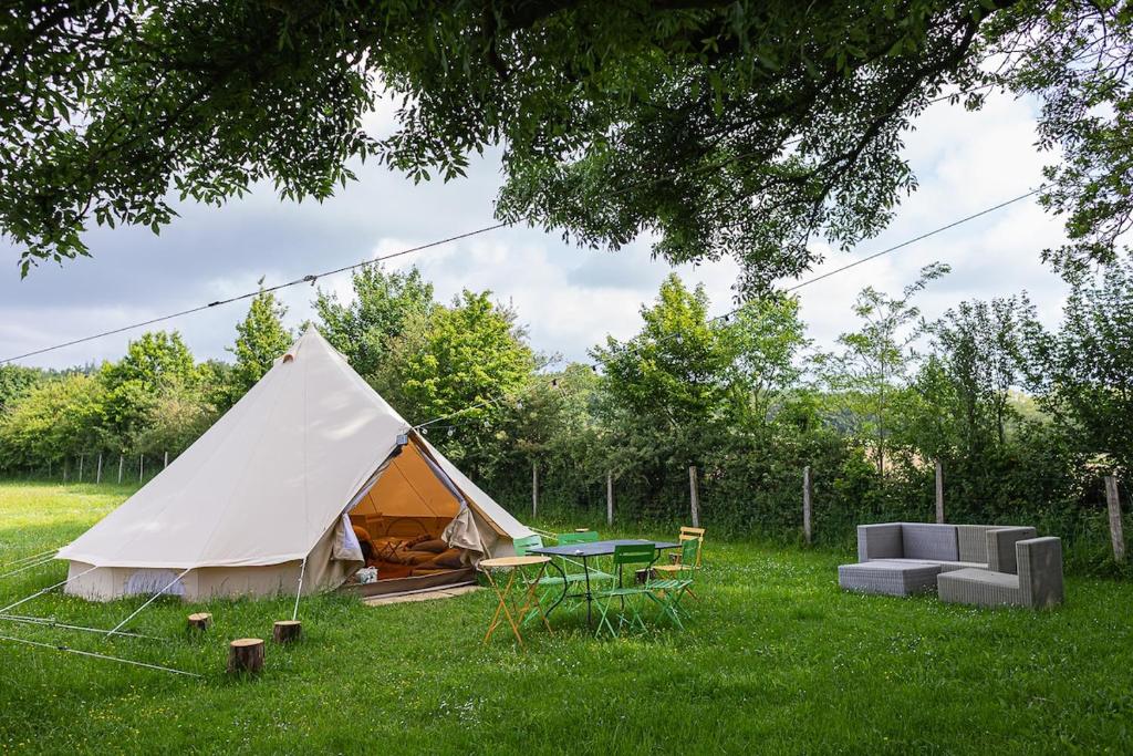une tente, une table et des chaises dans un champ dans l'établissement Nuit *é* Toilée à la Ferme du Petit Puyaume, à Montravers