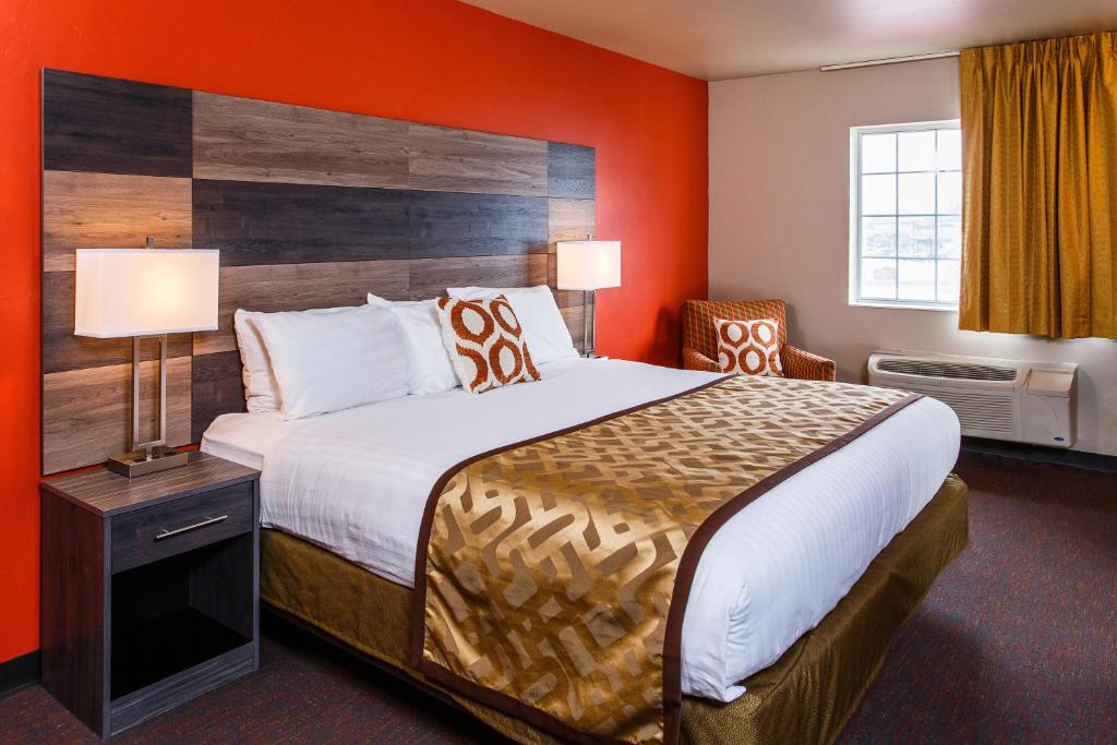 a hotel room with a large bed with orange walls at Hotel J Green Bay in Green Bay
