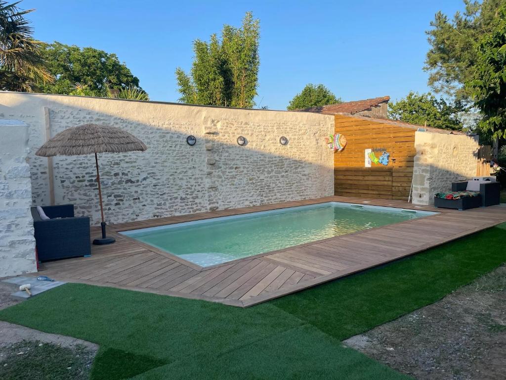 una piscina con una terraza de madera y una sombrilla en Maison confortable à Jard-sur-Mer avec grand jardin clôturé, en Jard-sur-Mer