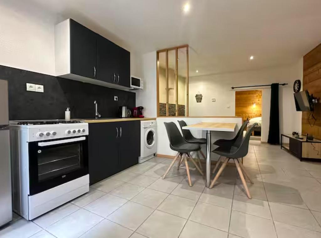 une cuisine avec des armoires noires, une table et des chaises dans l'établissement Le Repaire Sarrecrochet, au Puy-en-Velay