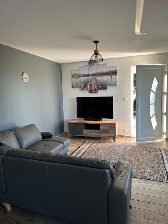 a living room with a couch and a flat screen tv at maison au calme in Maubourguet