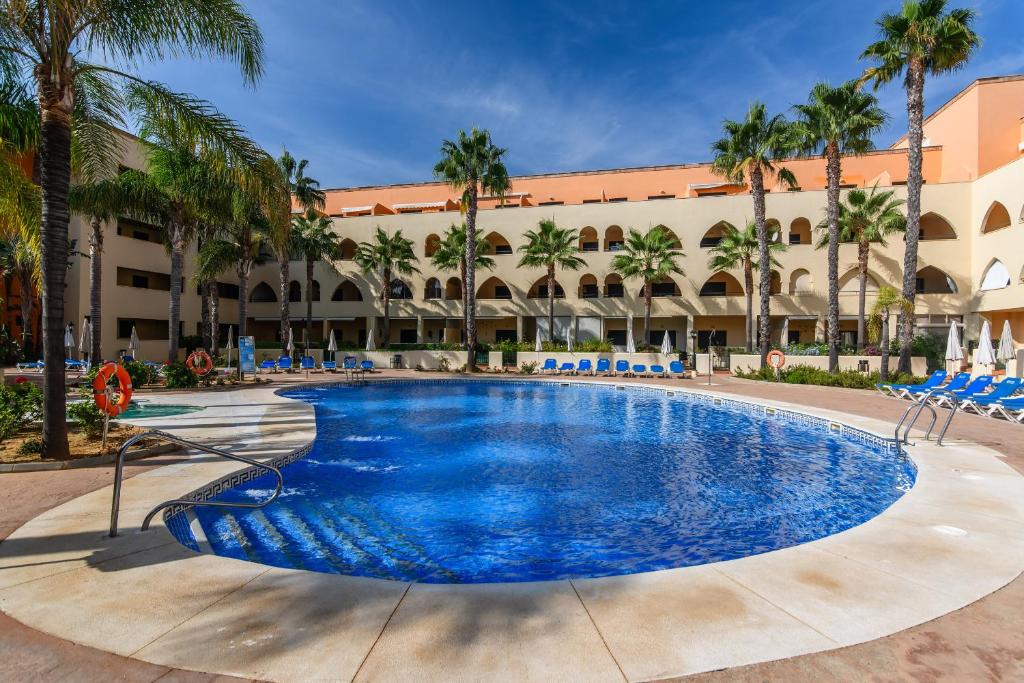 einem großen Pool mit blauen Stühlen und einem Gebäude in der Unterkunft Playa Marina by Ĥ - Playa Punta del Moral PPHM319P74 in Punta del moral