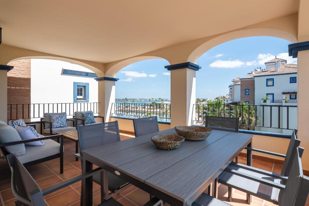 ein Holztisch und Stühle auf einem Balkon in der Unterkunft Marina I PLUS by Ĥ - Marina Isla Canela PMHI57P28 in Punta del moral