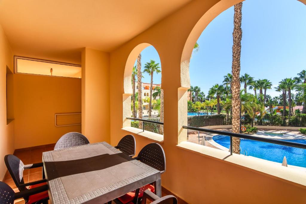 ein Balkon mit Tisch und Stühlen und ein Swimmingpool in der Unterkunft Playa Marina by Ĥ - Playa Punta del Moral PPHM218P41 in Punta del moral
