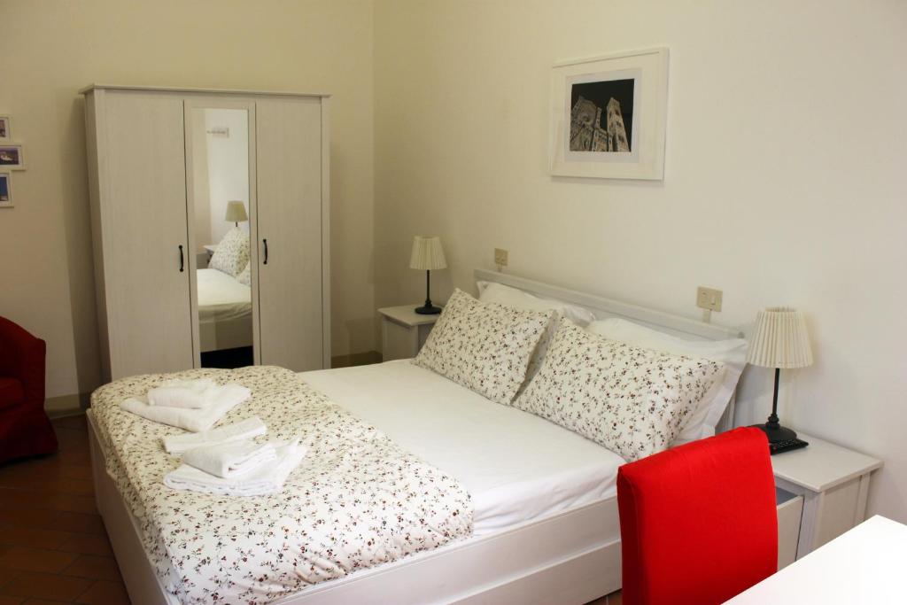 1 dormitorio con 1 cama con silla roja y espejo en Michelangelo's Relais, en Florencia