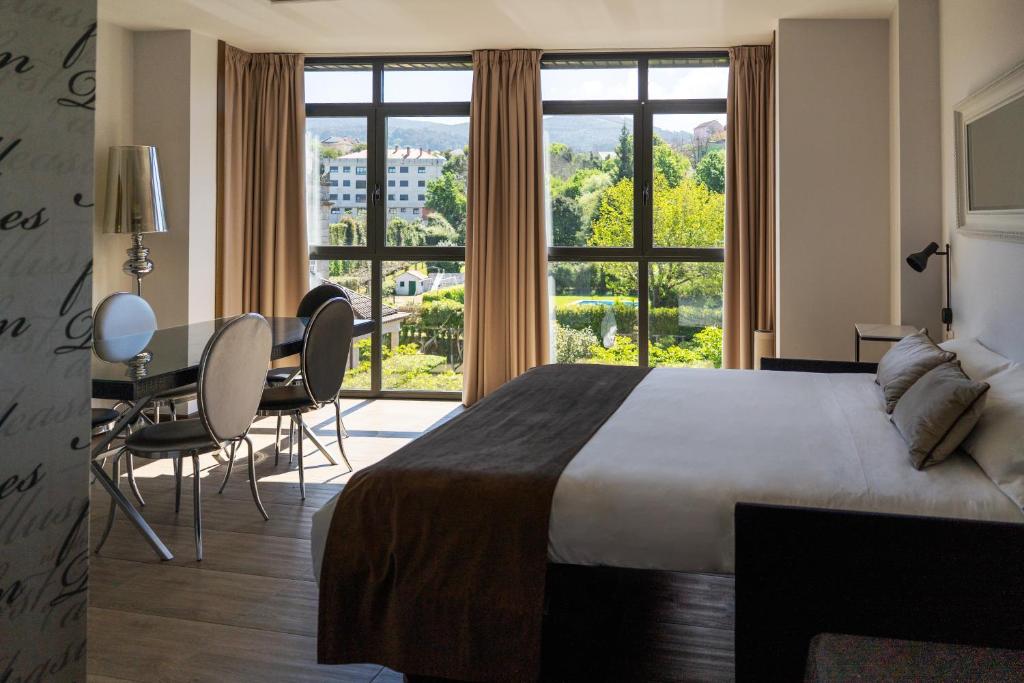 pokój hotelowy z łóżkiem, stołem i krzesłami w obiekcie Alvear Suites w mieście Redondela