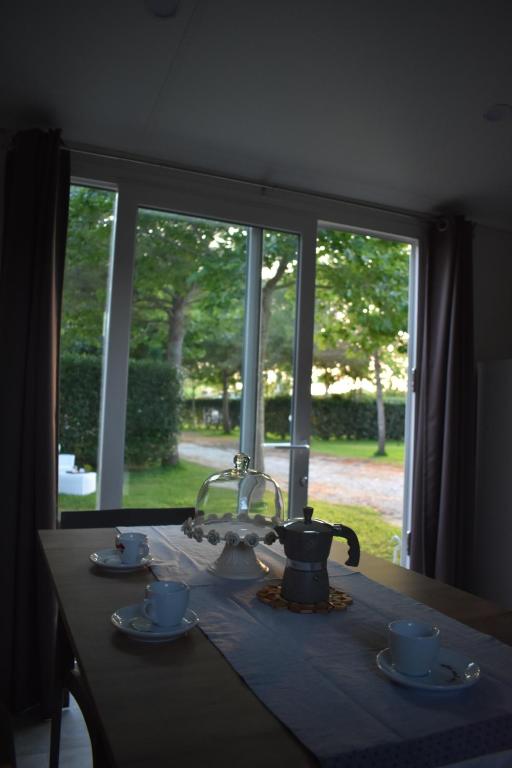 a table with a tea kettle and cups and a window at OasiHome in SantʼAndrea