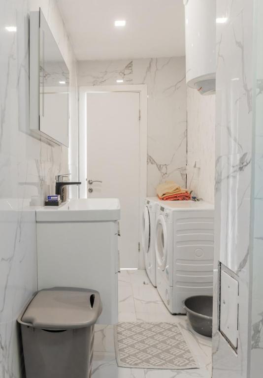 a white bathroom with a sink and a washing machine at Sea side apartment in Kotor