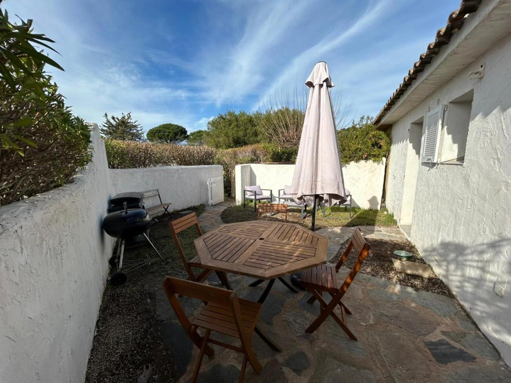 un patio avec une table, un parasol et un barbecue dans l'établissement Villa 625 Marina di Santa Giulia proche plage, à Porto-Vecchio