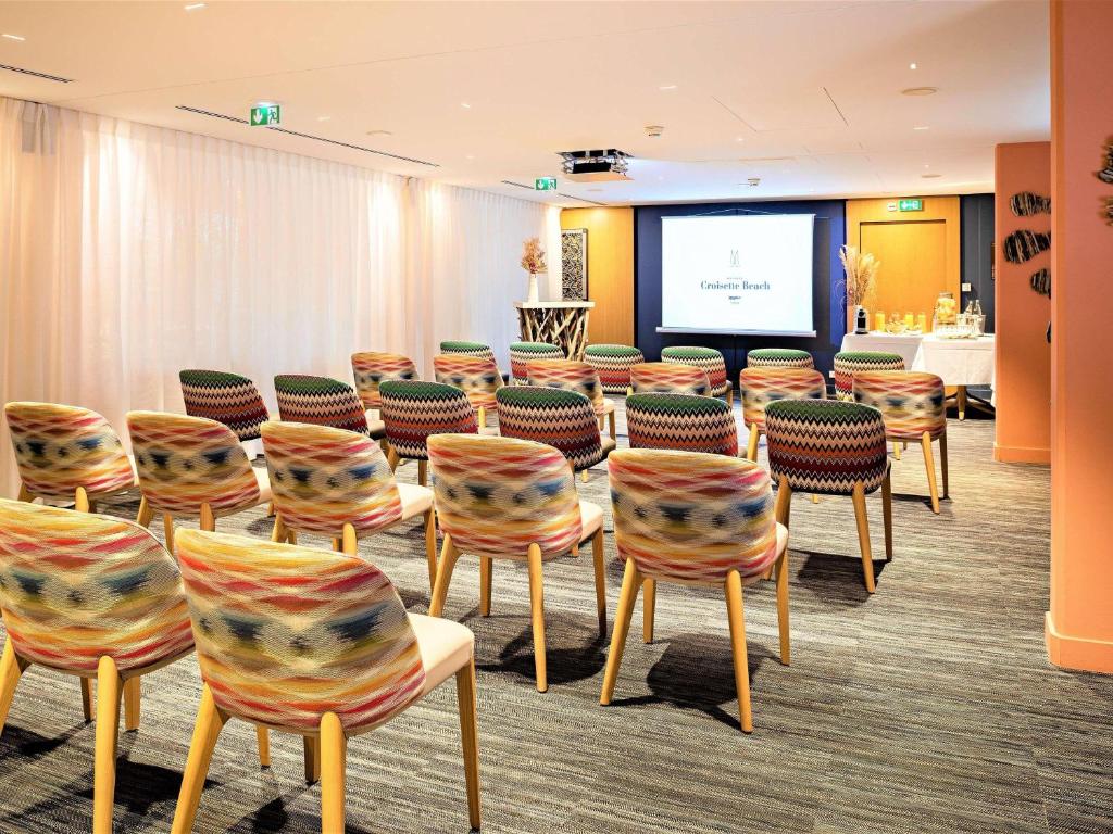 a conference room with chairs and a projection screen at Croisette Beach Hotel Cannes - MGallery Collection in Cannes