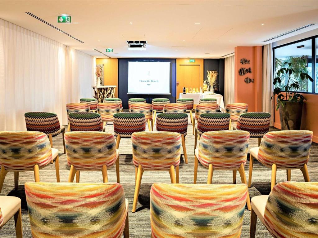 a conference room with chairs and a projection screen at Croisette Beach Hotel Cannes - MGallery Collection in Cannes