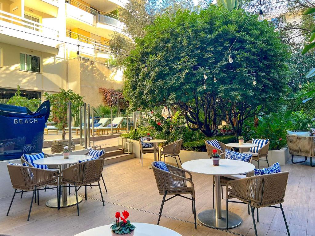 a patio of a restaurant with tables and chairs at Croisette Beach Hotel Cannes - MGallery Collection in Cannes