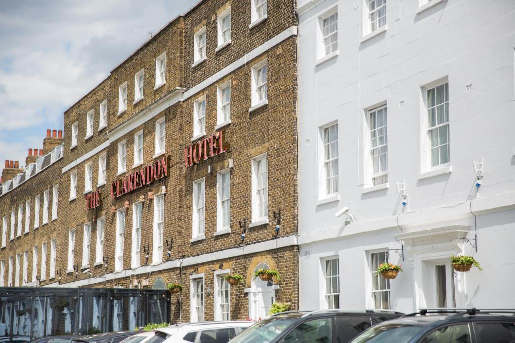 un grand bâtiment en briques avec des voitures garées devant lui dans l'établissement The Clarendon Hotel, à Londres