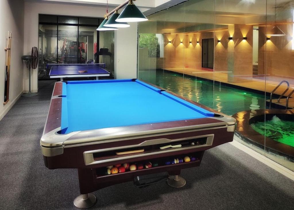 a pool table in a room with a swimming pool at Dar Al Habib in Dhaka