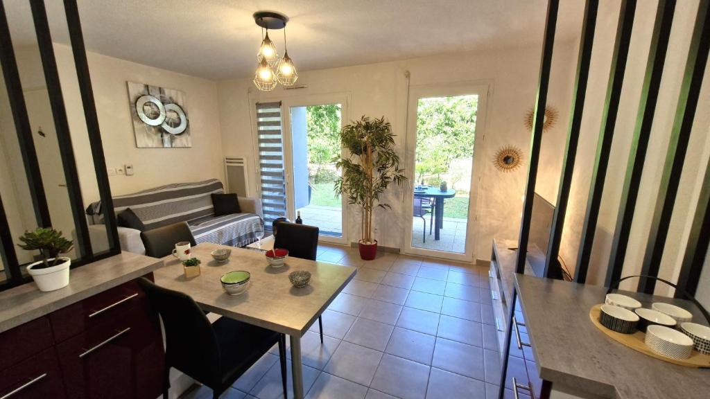 une cuisine et un salon avec une table et des chaises dans l'établissement Royan - APPARTEMENT en rez-de-chaussée aménagé avec ELEGANCE - jardin privatif, à Royan