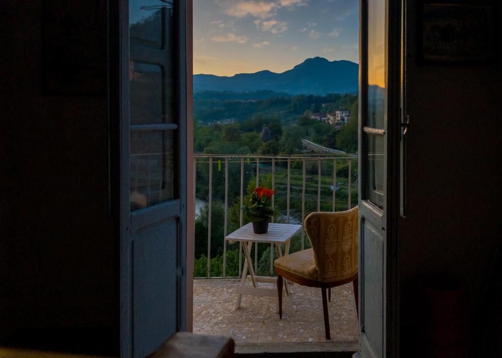 Otwarte drzwi na balkon ze stołem i krzesłem w obiekcie BENVENUTI A CASA PAOLA , WELCOME IN GARFAGNANA! w mieście Castelnuovo di Garfagnana