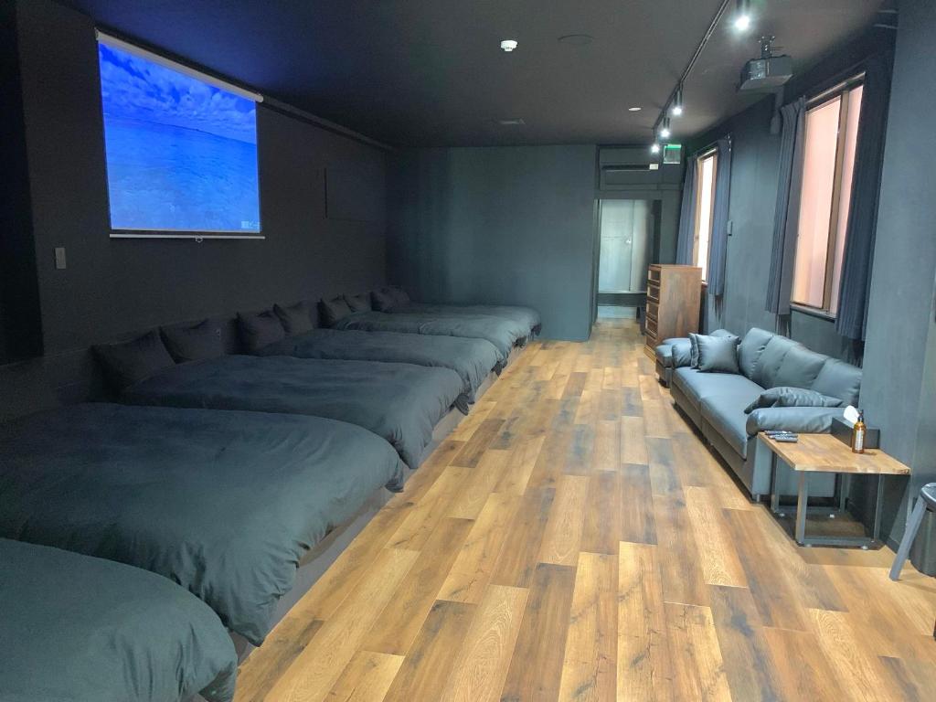 a room with a row of beds and a couch at Black Penthouse Naha 最大12名宿泊可 118平米 国際通り沿い 牧志駅 徒歩5分 in Naha