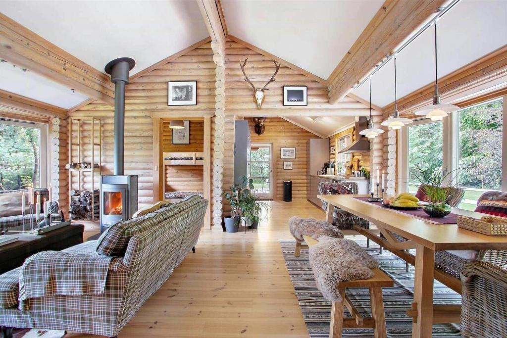 sala de estar con paredes de madera, mesa y sillas en Log Cabin Near Mariager Fjord, en Hadsund