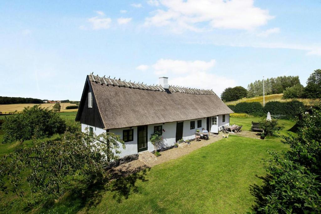 una casa blanca con techo gris en un campo verde en Cottage Charm Near Svebølle Amidst Fields, en Svebølle