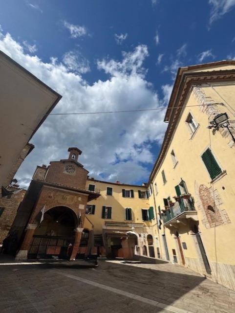 a building with a clock tower on the side of it at La Casa in Piazza in Serre di Rapolano