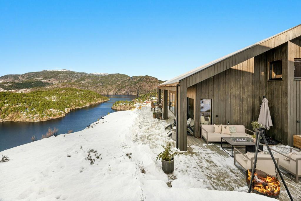 a house with snow on the ground next to a river at Cabin Overlooking Ryfylke Fjord in Høyvik