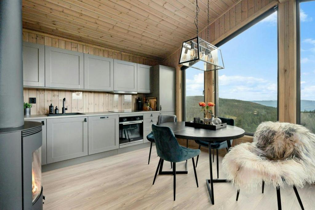 una cucina con tavolo e sedie e una grande finestra di Norefjell Cottage With Sauna And Whirlpool a Noresund