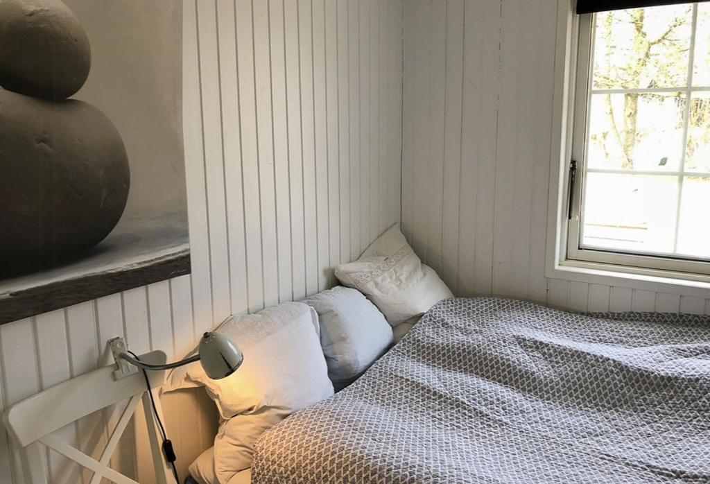 a bedroom with a bed and a window at Beach-Close Wooden Summer House In Tversted in Tversted