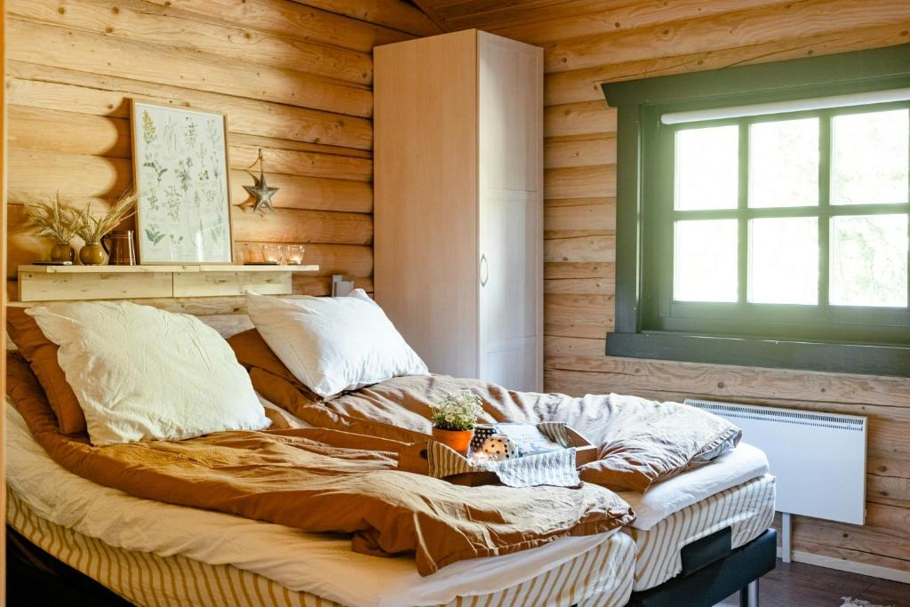 ein Bett in einem Zimmer mit einer Holzwand in der Unterkunft Authentic Log House Amid Evergreens In Vendsyssel in Fjerritslev
