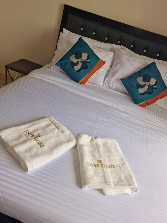 Una cama blanca con toallas encima. en Drift and Dream, en Syokimau
