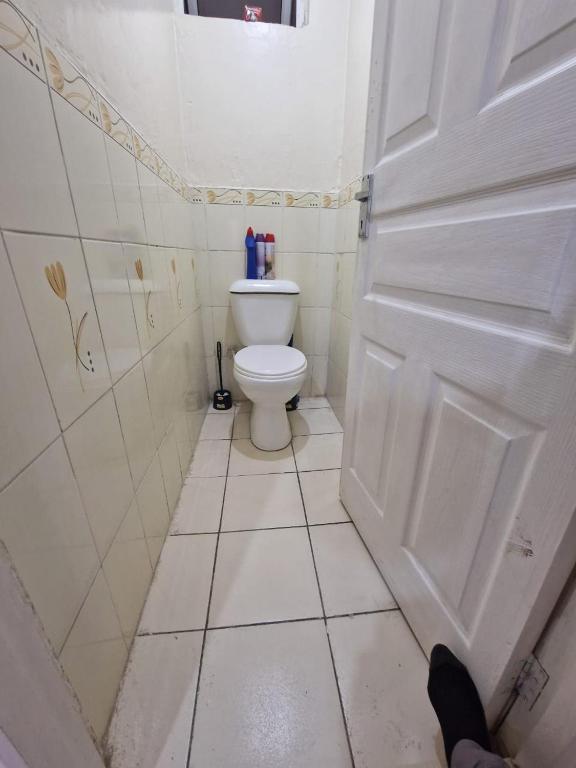 Baño blanco con aseo y puerta en Drift and Dream, en Syokimau