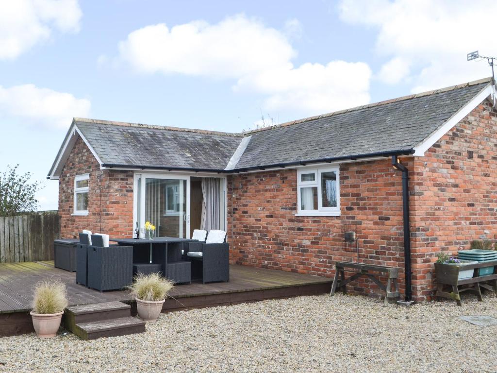 a brick house with a wooden deck at The Cockles in Ulgham