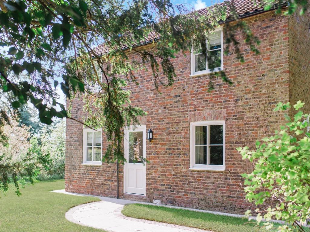 ein rotes Backsteinhaus mit einer weißen Tür in der Unterkunft Gardeners Cottage in Saltmarshe