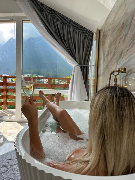 a woman in a bath tub with a glass of wine at Casa Anitta in Buşteni