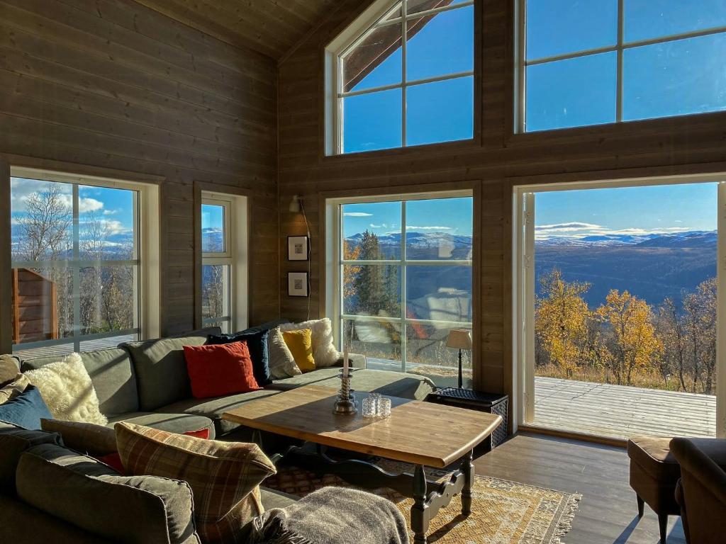 a living room with a table and large windows at Traditional Cabin With Views Of Hardangervidda in Uvdal
