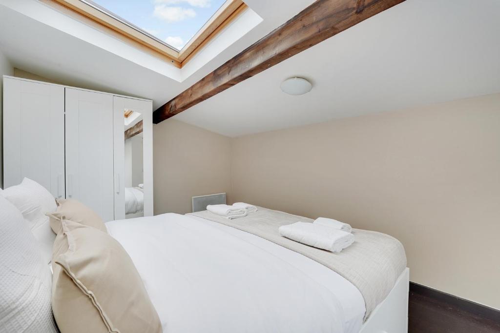 une chambre blanche avec un lit blanc et une fenêtre dans l'établissement Maison équipée à Pantin Idéal pro & famille, à Pantin