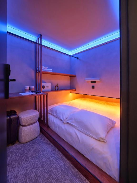 a bedroom with a large bed with a blue lighting at The Hyve Capsule Amsterdam in Amsterdam