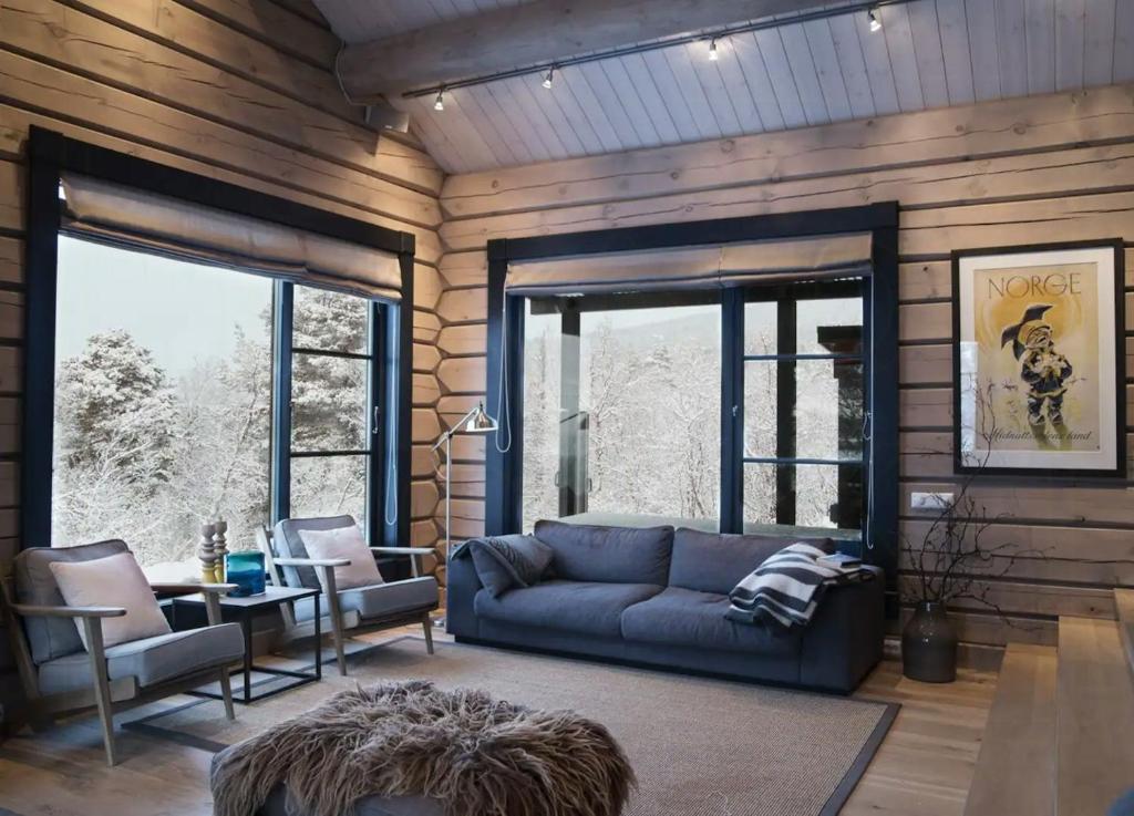 オップダールにあるSpacious Mountain Cabin With Lodge Style In Oppdalのリビングルーム(青いソファ、一部の窓付)