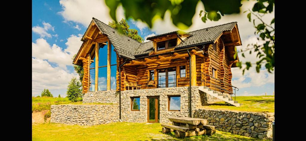 a large log cabin with a stone wall at Poeme Chalet in Râșca