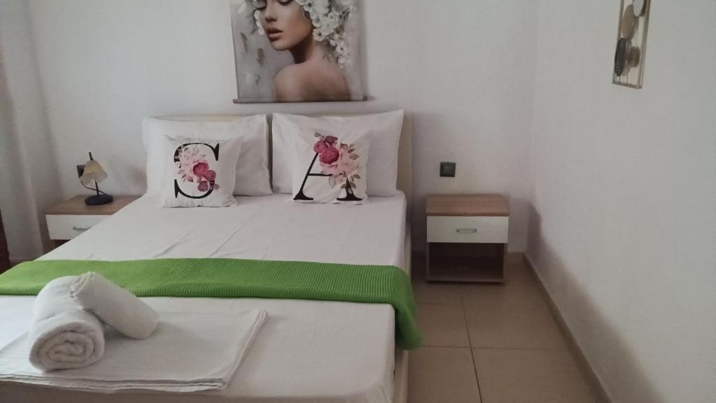ein weißes Bett mit einer grünen Decke und zwei Kissen in der Unterkunft Anastelia Apartments - 2 in Olympiada