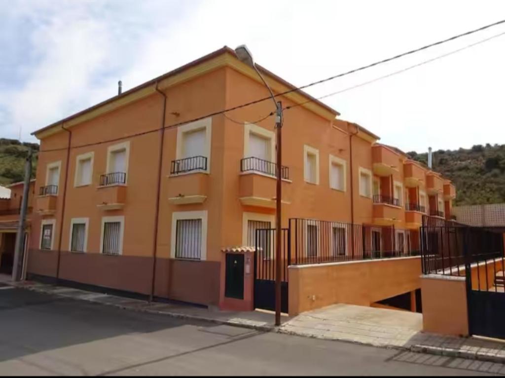 an orange building with a fence in front of it at apartamento los montes in Ruidera