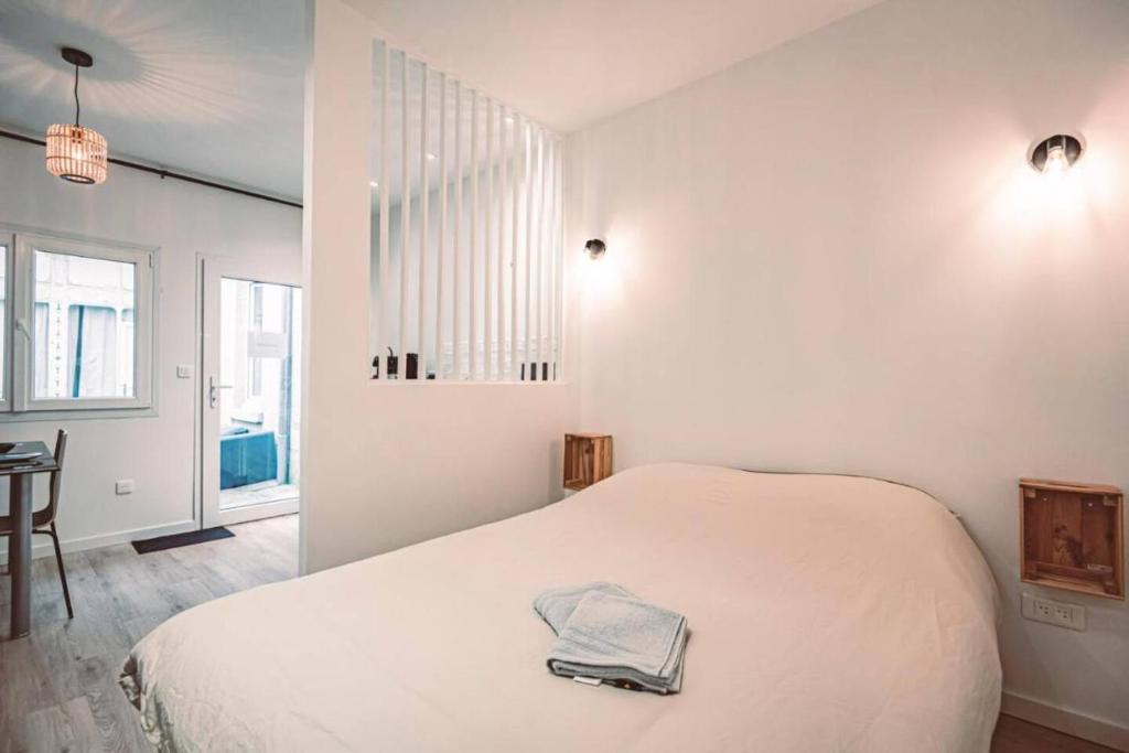 une chambre blanche avec un lit et une table dans l'établissement Socotra - Appartement chaleureux - Hyper-centre, à Reims