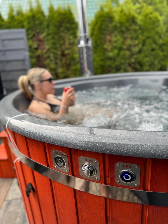 a woman is sitting in a hot tub at Maharówka - Domki z sauną i balią - Ostrowo - holiday home in Ostrowo